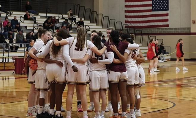 Women's basketball team in a group huddle on the court